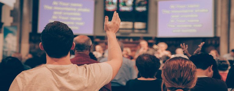 Church worshippers with lyrics projected onto big screens